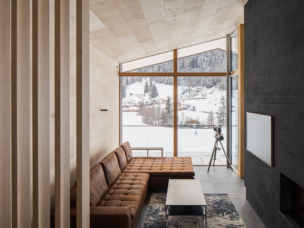Spacious snow-covered mountain retreat with cozy oversized leather sofa, modern furnishings.