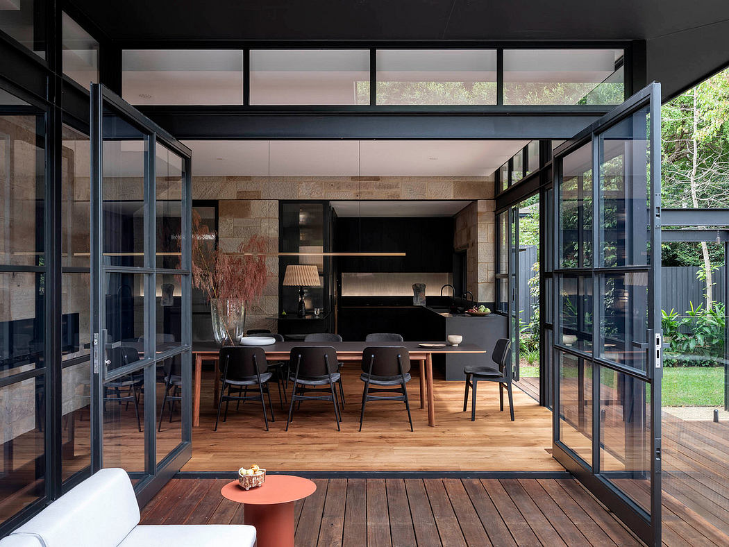 A modern open-plan living space with expansive glass walls overlooking lush greenery.