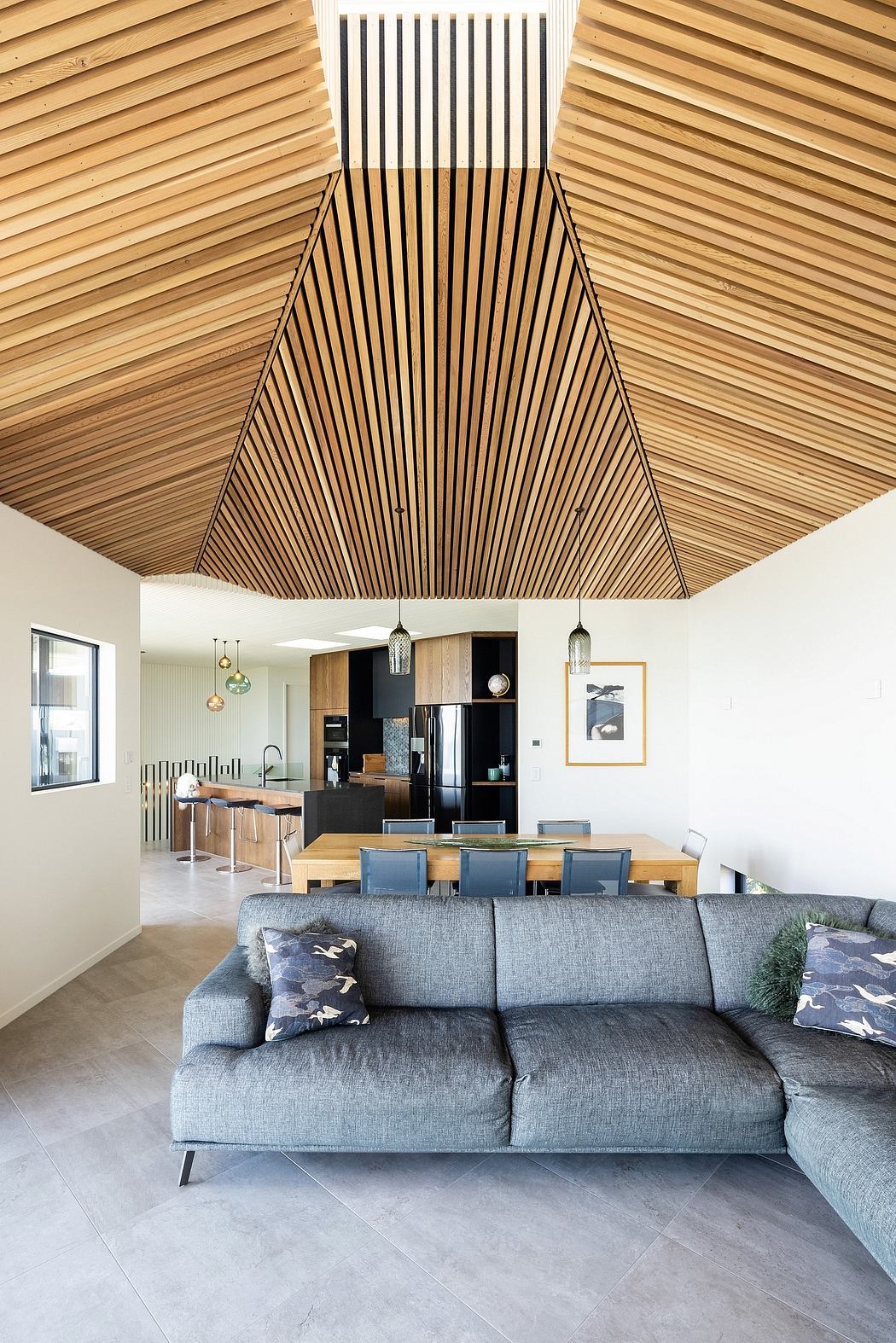Striking angular wood ceiling, neutral color palette, and open living/dining space.