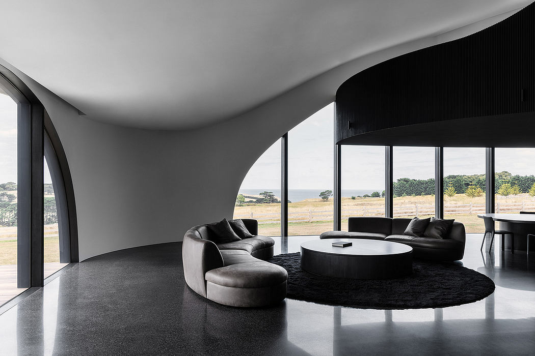 Minimalist living room with curved black sofa, round coffee table, and expansive windows.