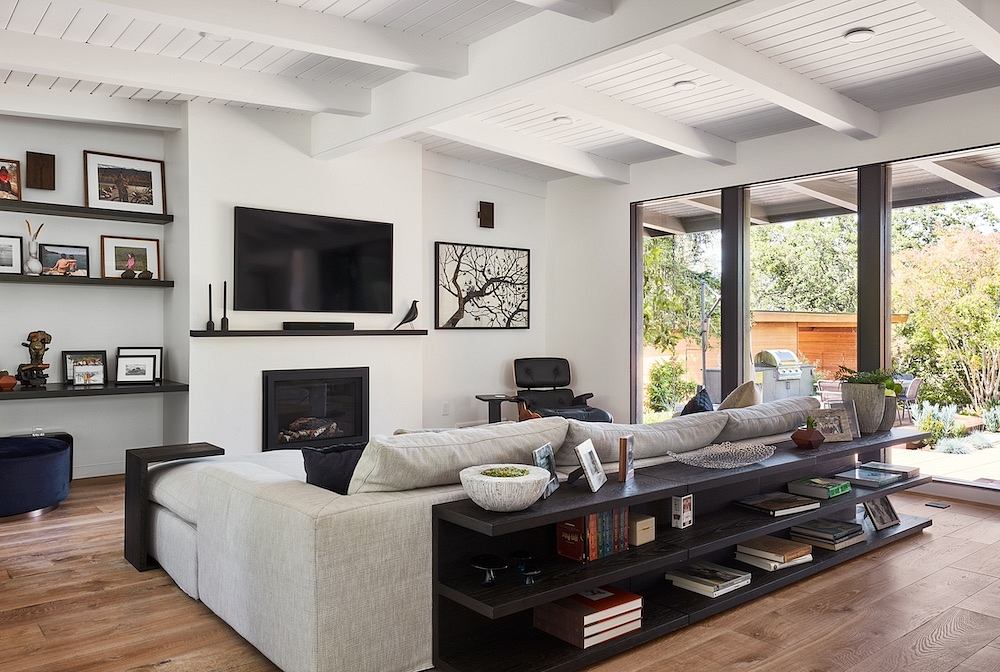 Spacious living room with fireplace, built-in shelves, and large windows overlooking the outdoors.