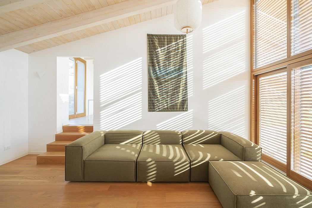 Bright, airy room with a wooden ceiling, large windows, and a modular tan sofa.