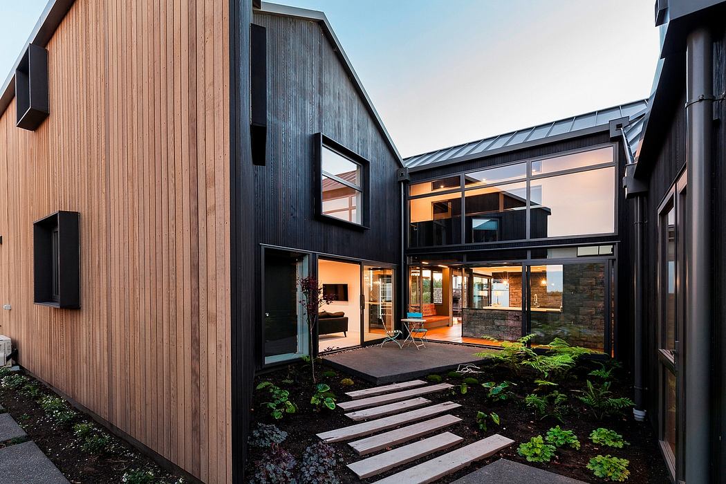 Sleek modern architecture with contrasting wooden and dark panels, leading to a warm interior.