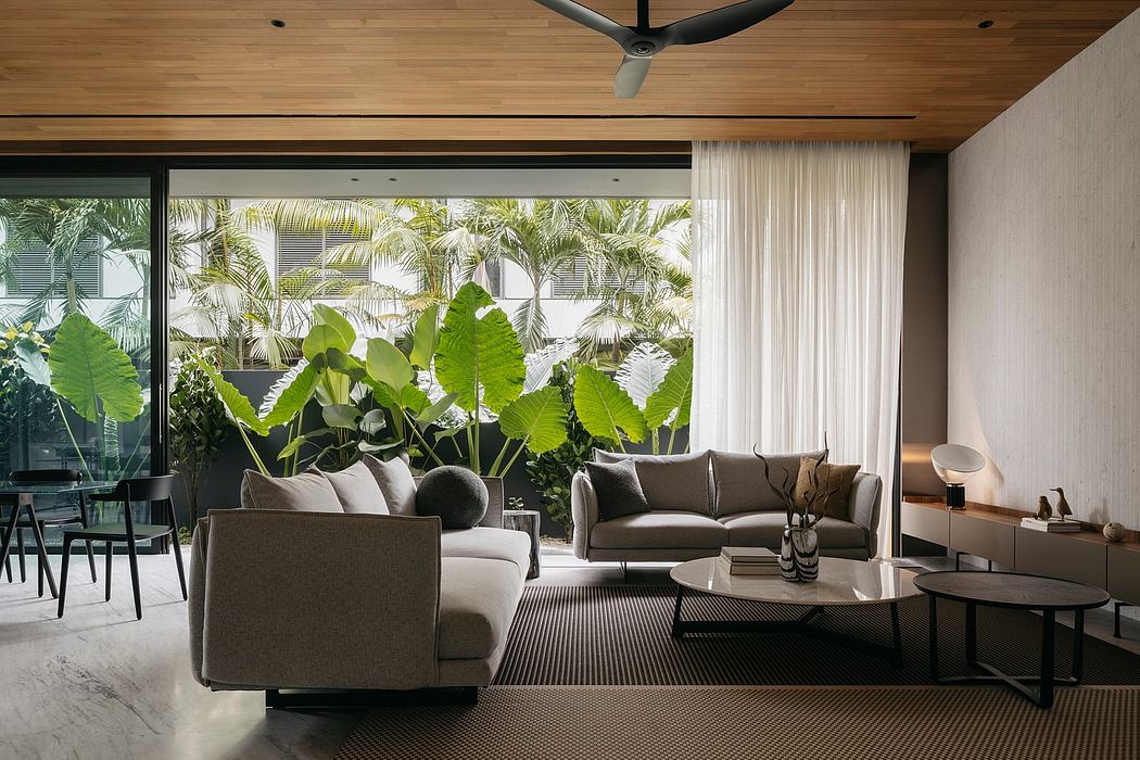 Lush tropical foliage frames a modern, open-concept living space with sleek furnishings.