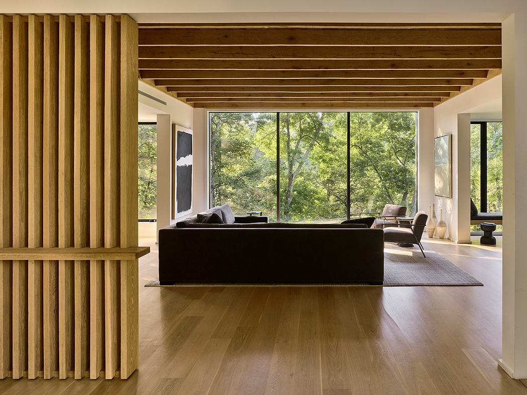 Spacious modern living room with wooden ceiling beams, large windows, and minimalist furniture.