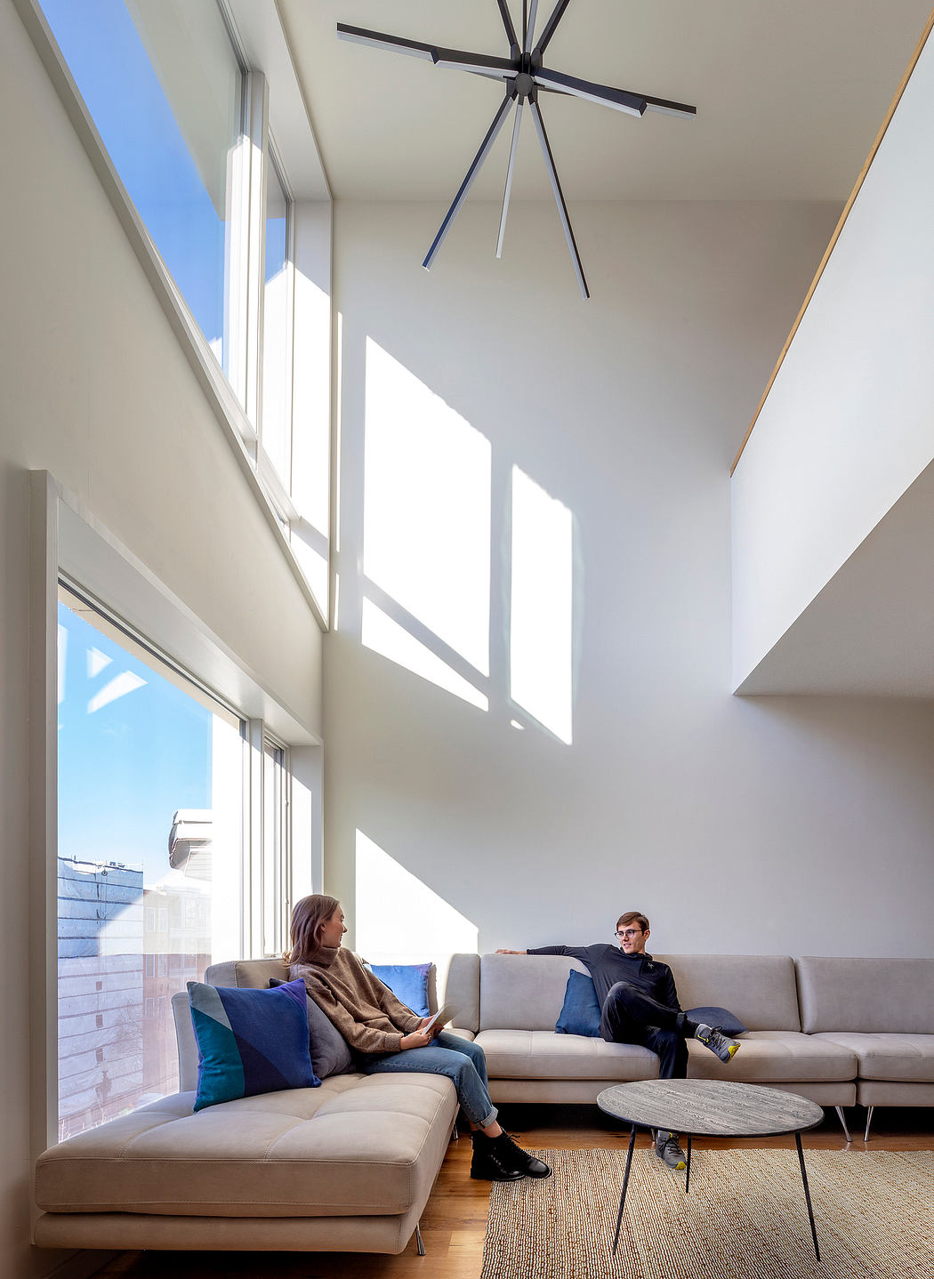 A modern, airy living space with high ceilings, large windows, and a striking light fixture.