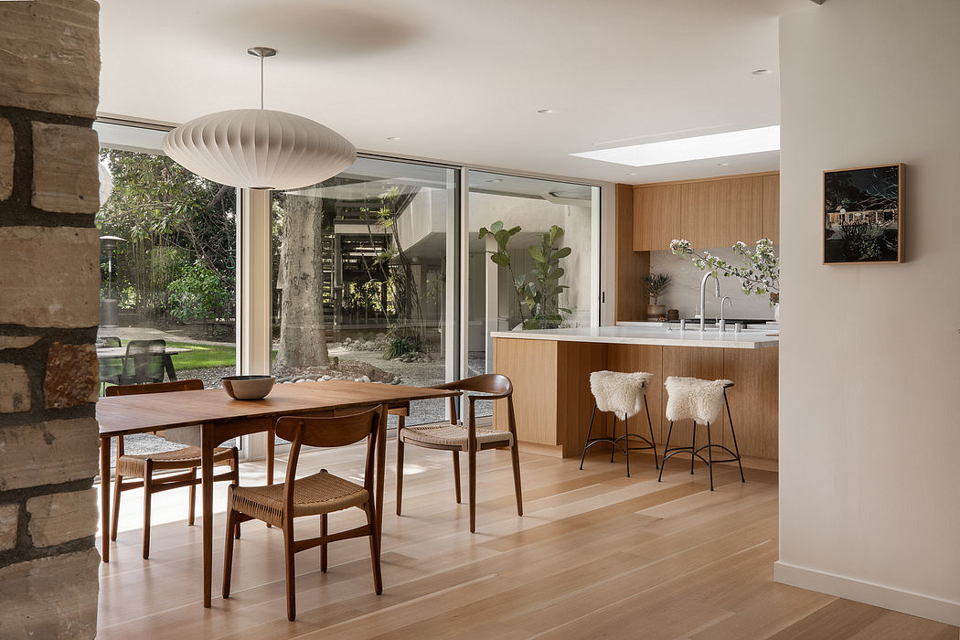 Minimalist open-concept kitchen and dining area with wooden furnishings and large windows.