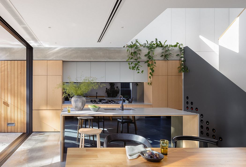 This modern kitchen features a sleek, minimalist design with wood cabinetry, a floating island, and hanging plants.