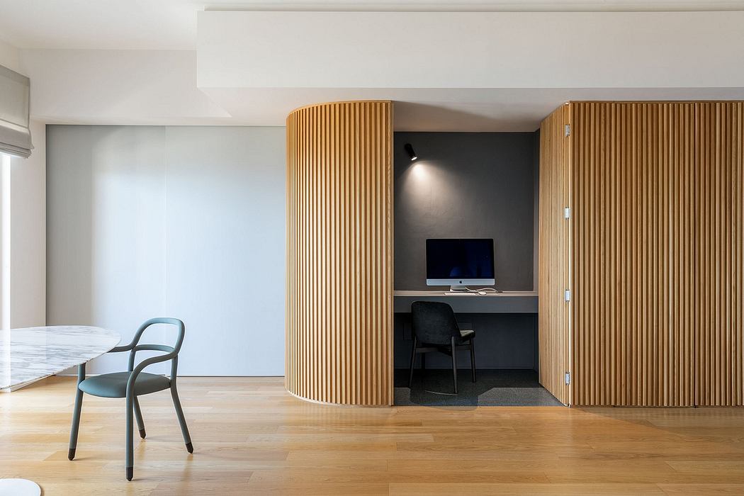A modern, minimalist room with wooden paneled walls, a desk nook, and a chair.