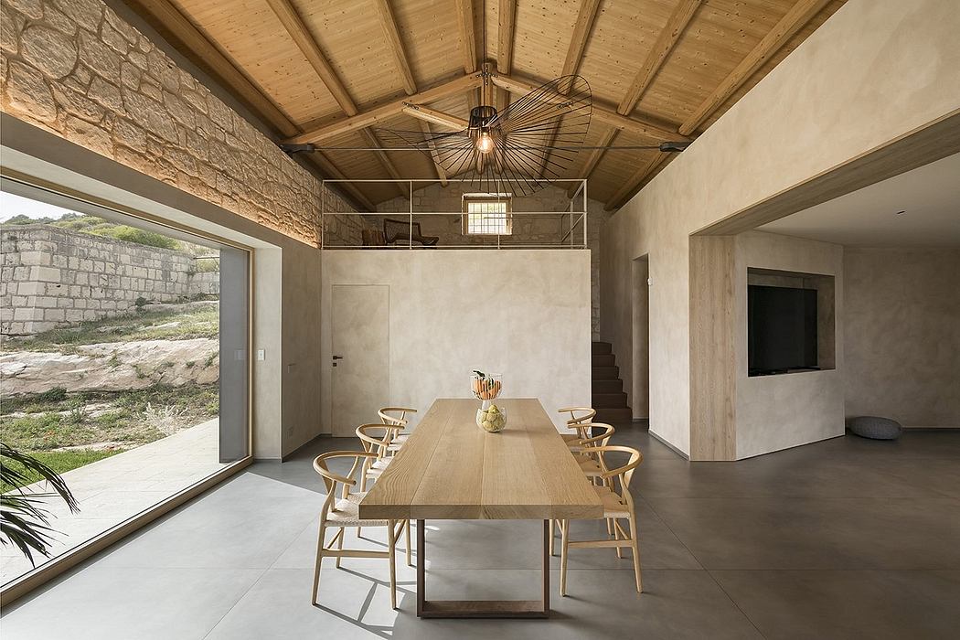 Rustic stone walls, exposed wooden beams, and a modern wood dining table with chairs.