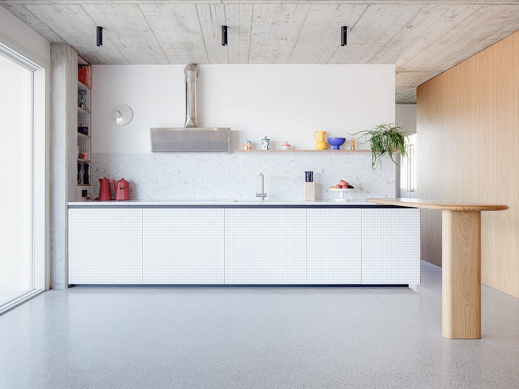 Minimalist kitchen with exposed concrete ceiling, white cabinets, and wood details.