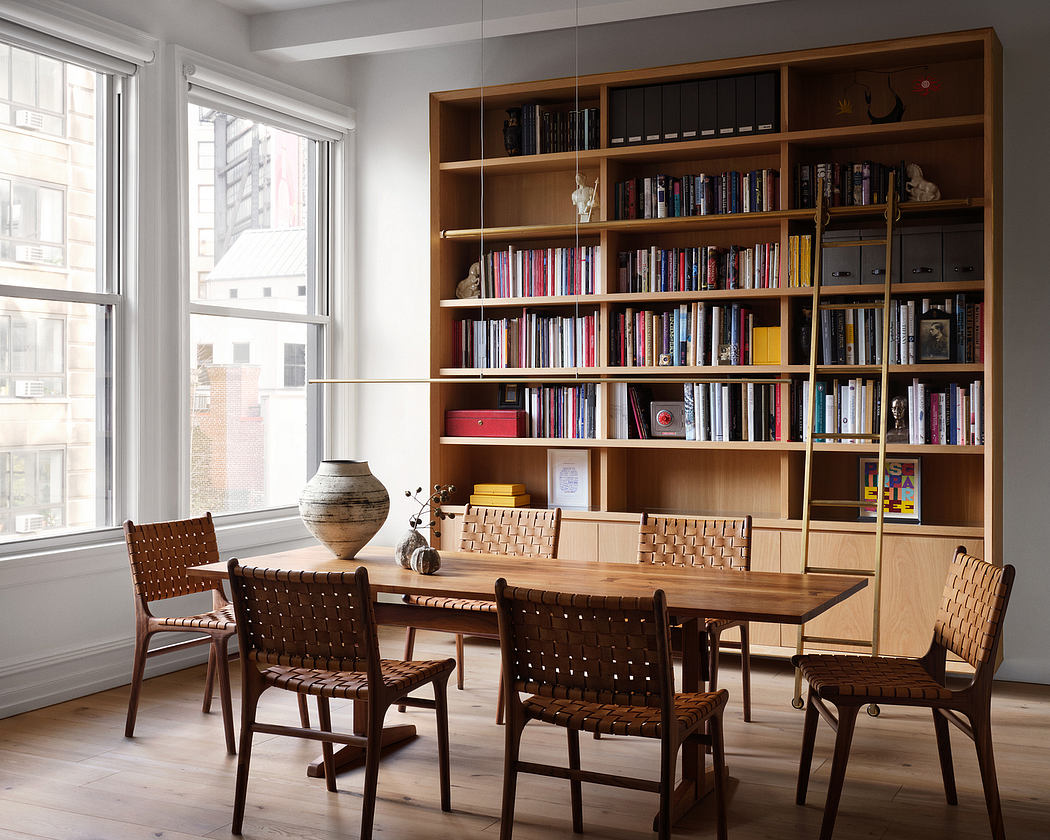 A bright, modern room with a wooden bookshelf, table, and woven chairs, showcasing a harmonious interior design.