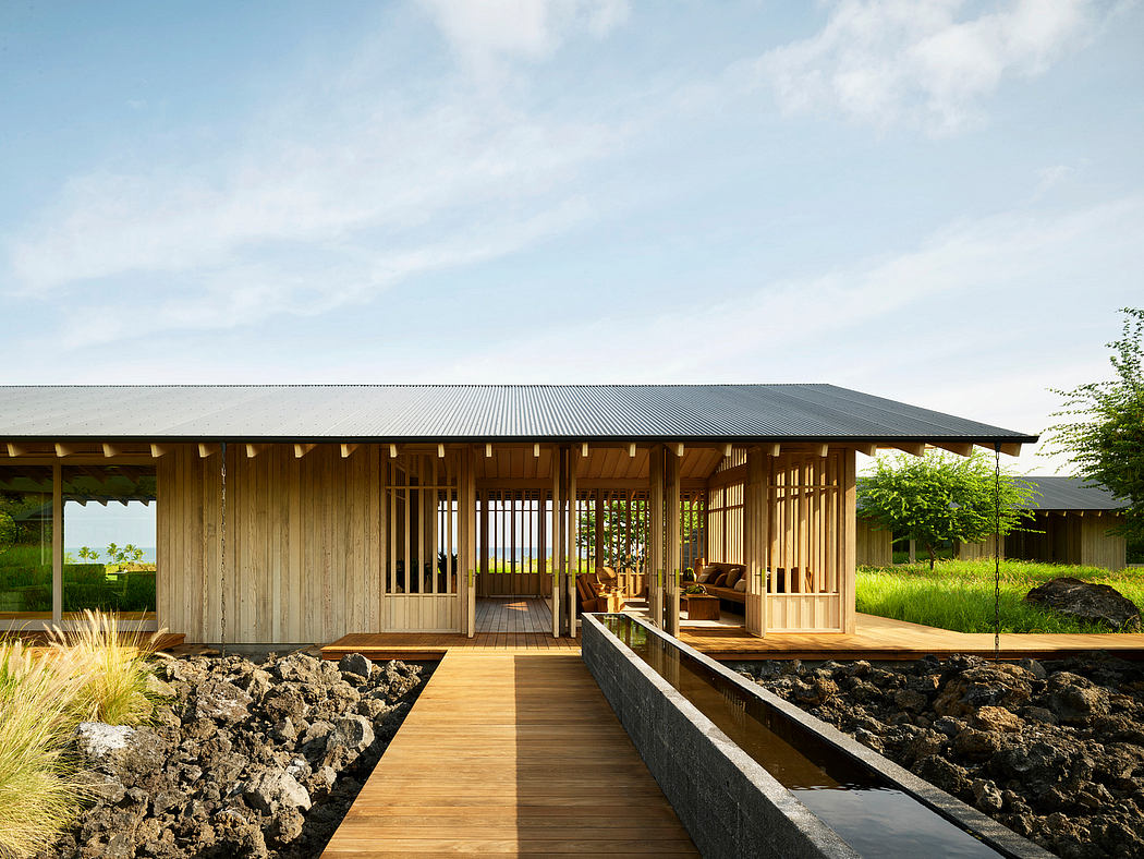 A rustic wooden cabin surrounded by lush greenery, with a wooden deck and a winding boardwalk leading to it.