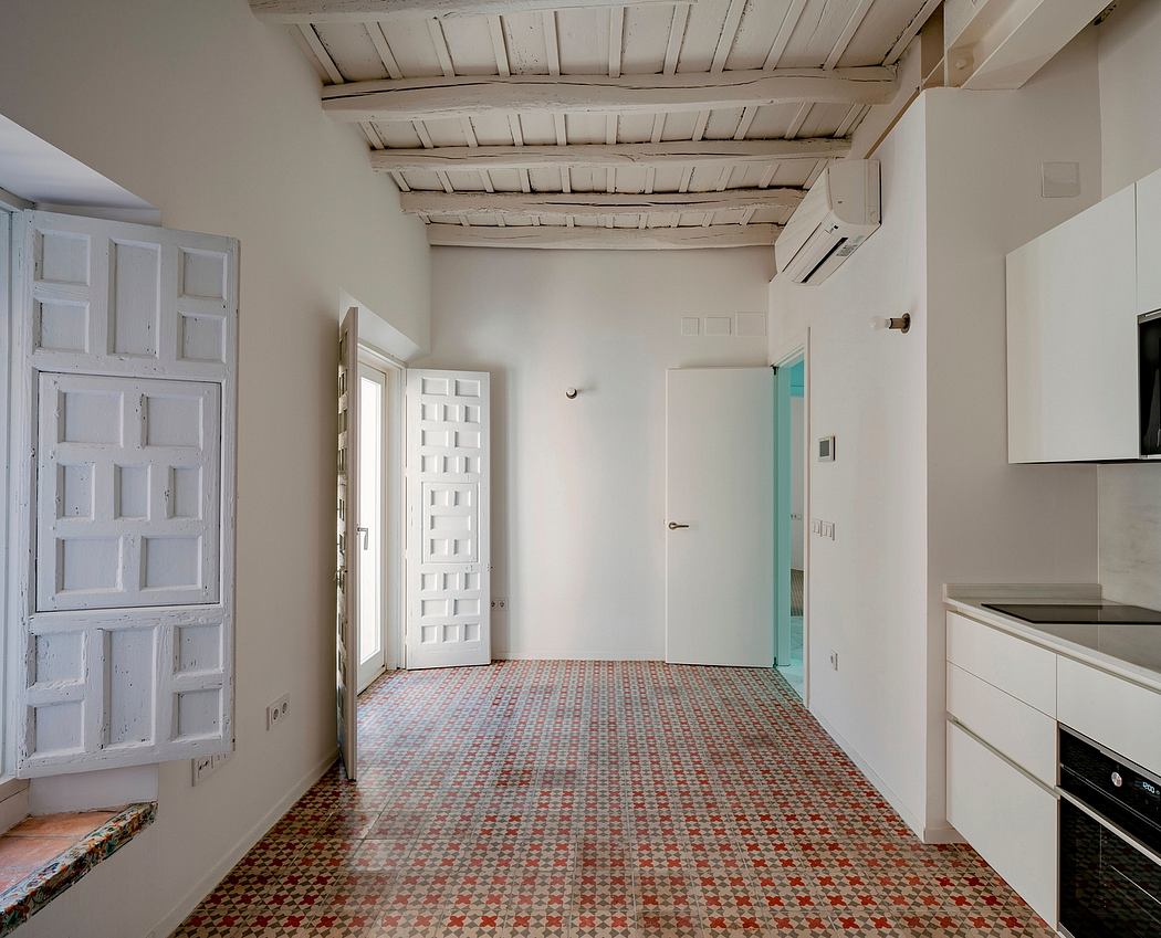 Spacious room with exposed wooden beams, patterned tile flooring, and a modern kitchen.