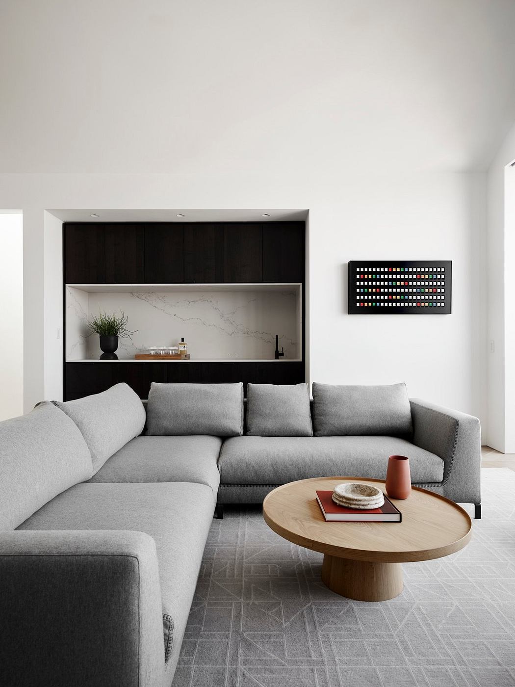 Minimalist living room with built-in shelving, gray sectional sofa, and wooden coffee table.