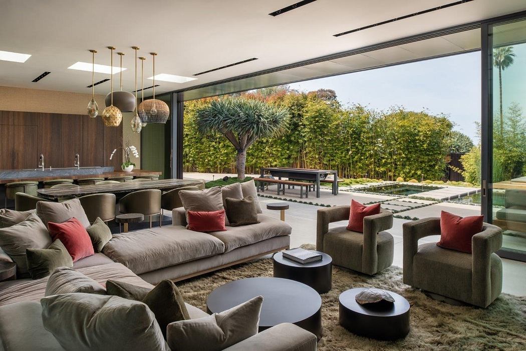 Spacious modern living room with large glass windows overlooking lush outdoor scenery.