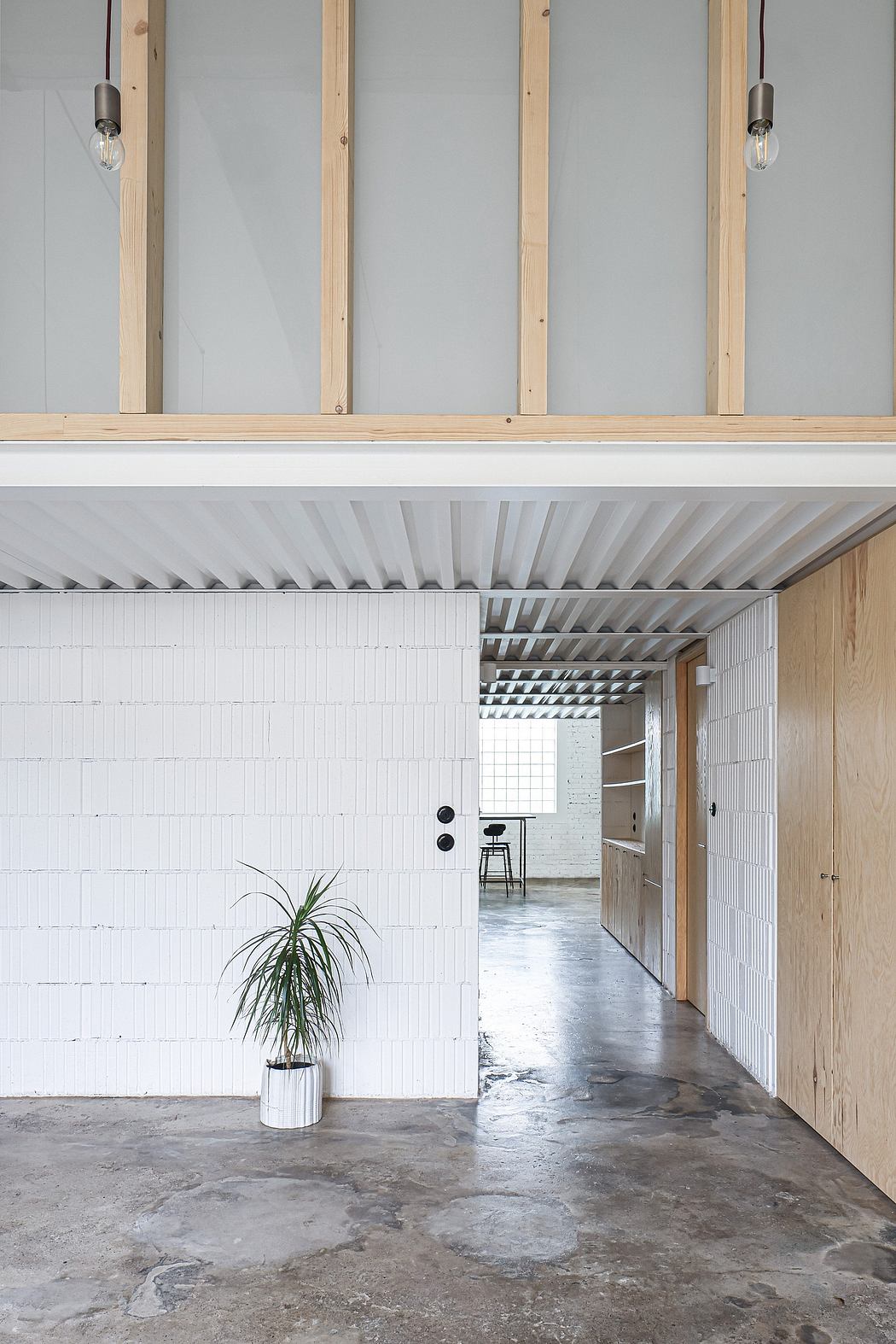 Minimalist architectural interior with white walls, wooden beams, and concrete flooring.