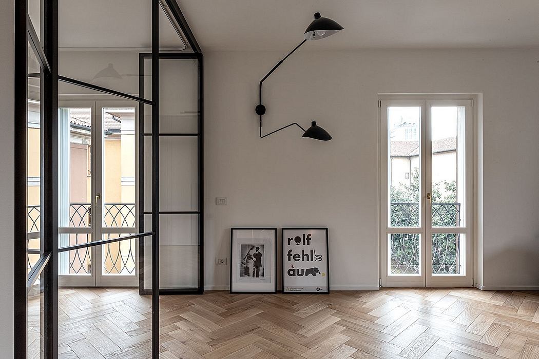 Modern, open-concept living space with wooden herringbone flooring, industrial-style lighting, and framed artwork.