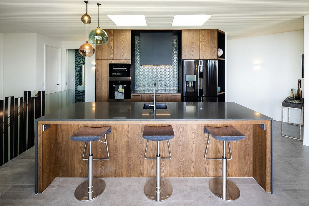 A modern kitchen featuring a sleek, dark countertop, wood cabinets, and pendant lighting.