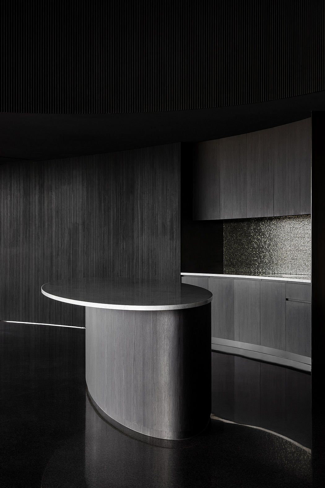 Striking black and white architectural design, with a sleek circular table and dark cabinetry.