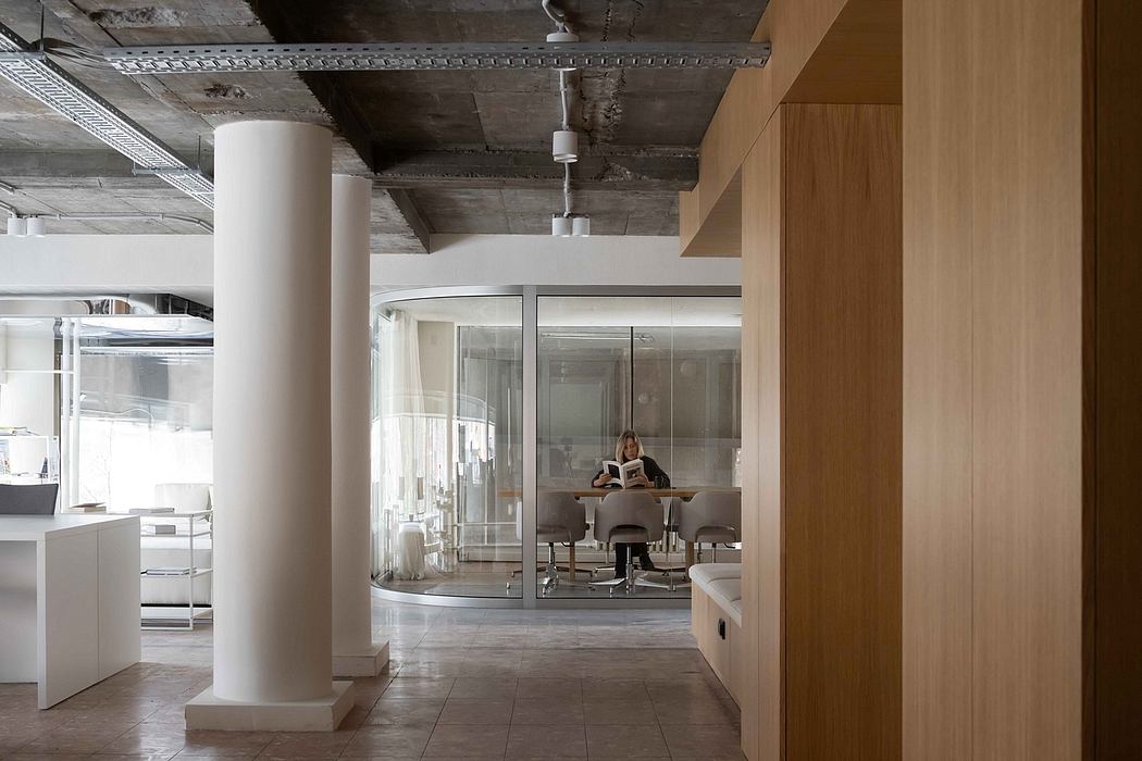 Modern, open-plan office with concrete ceiling, glass walls, and wood accents.