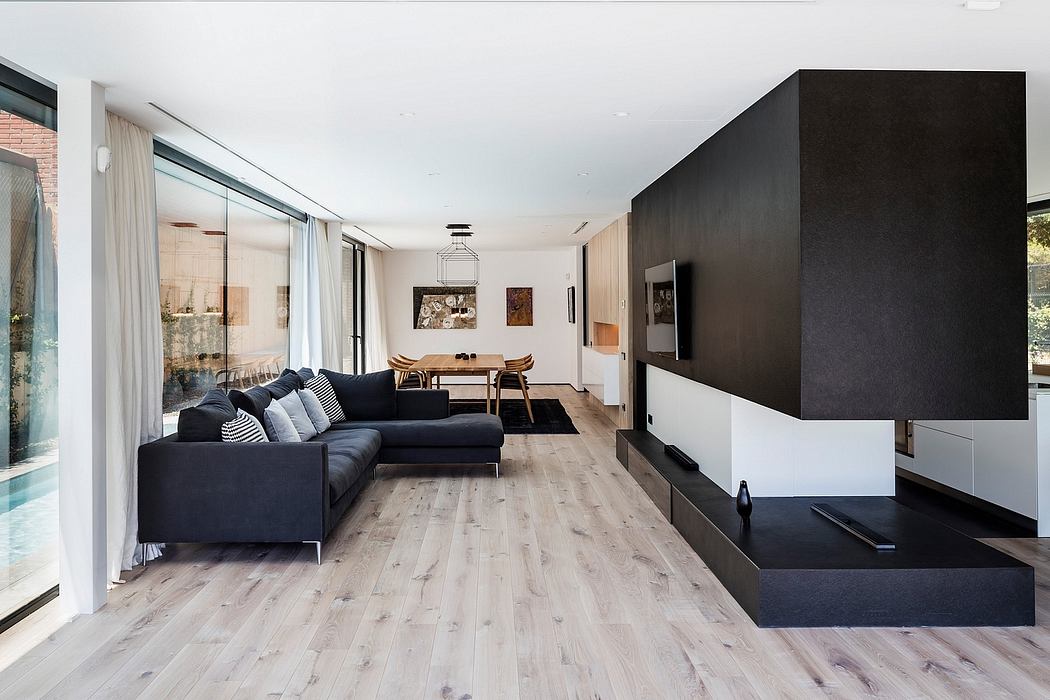 Minimalist living room with sleek black and white decor, large sectional couch, and wooden flooring.