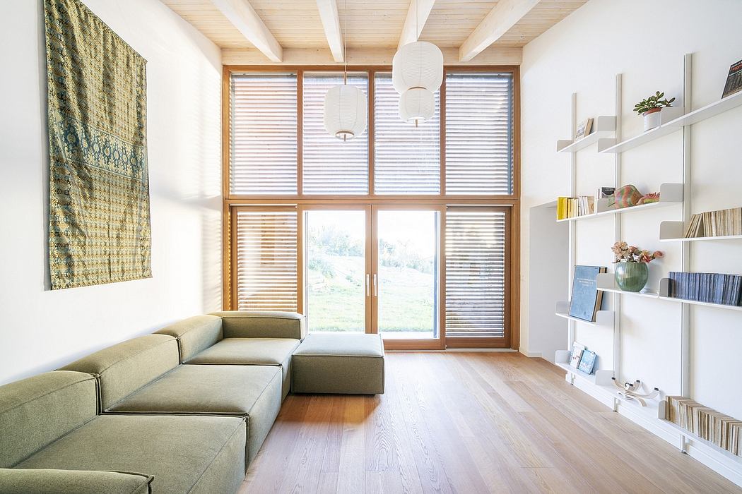Light-filled open-plan living room with wood-beamed ceiling, modular sofa, and built-in shelving.