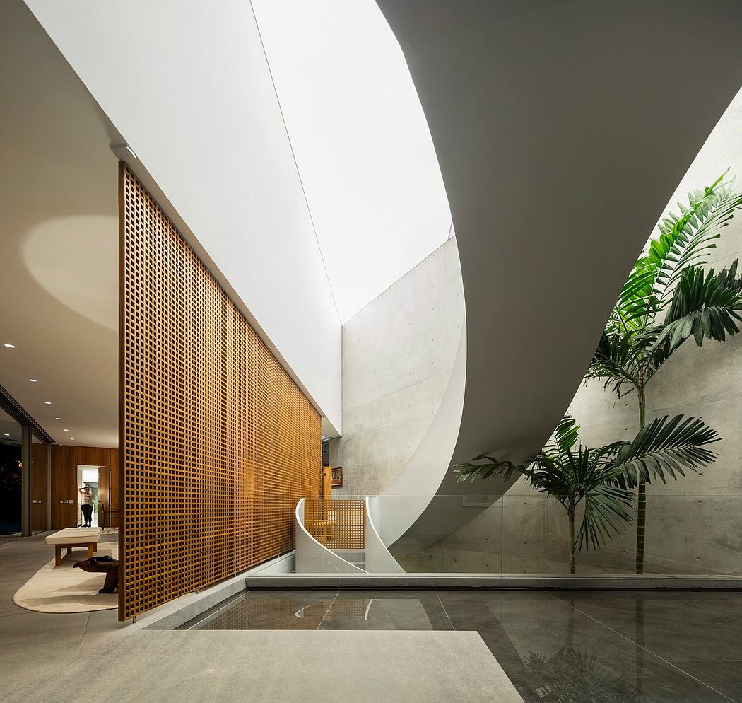 Minimalist lobby with wooden paneling, skylights, and lush tropical plants.