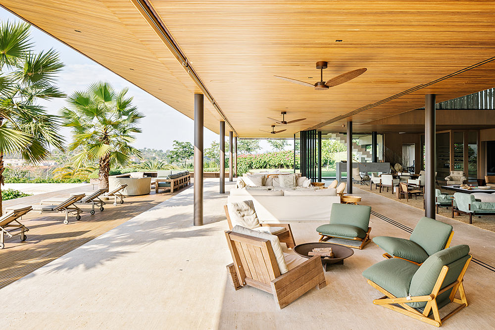 Spacious covered patio with wooden ceiling, lounge seating, and views of surrounding greenery.