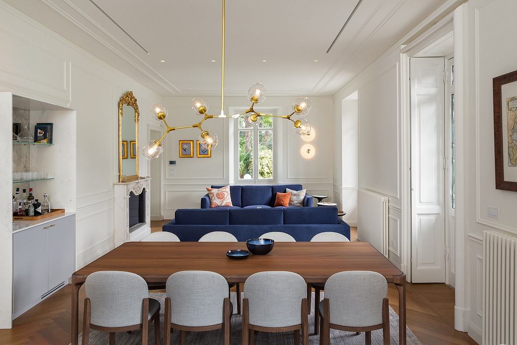 Elegant open-plan living space with ornate lighting, plush navy sofa, and wooden dining table.