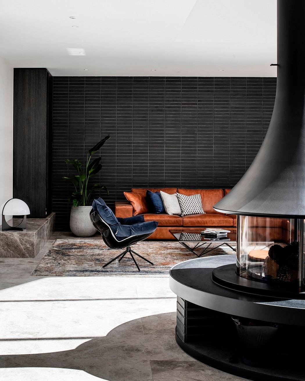Sleek, modern living room with a cozy leather sofa, textured accent wall, and sculptural fireplace.