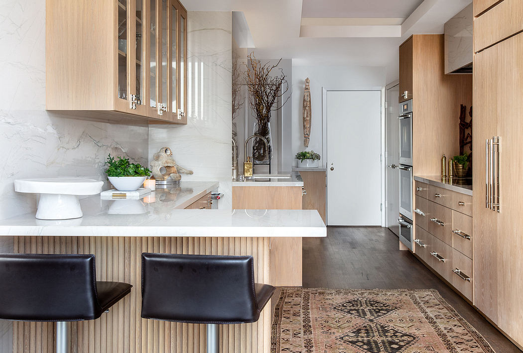 A modern kitchen with wooden cabinets, marble countertops, and a stylish rug on the floor.