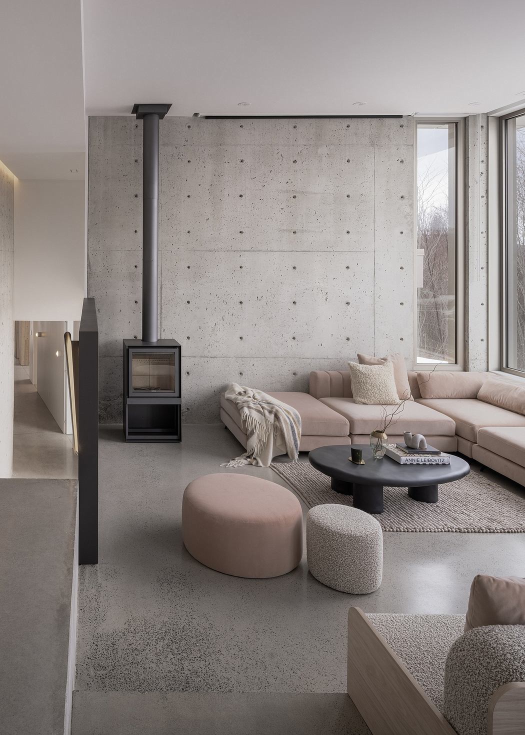 Minimalist living room with concrete walls, sleek furniture, and a central fireplace.
