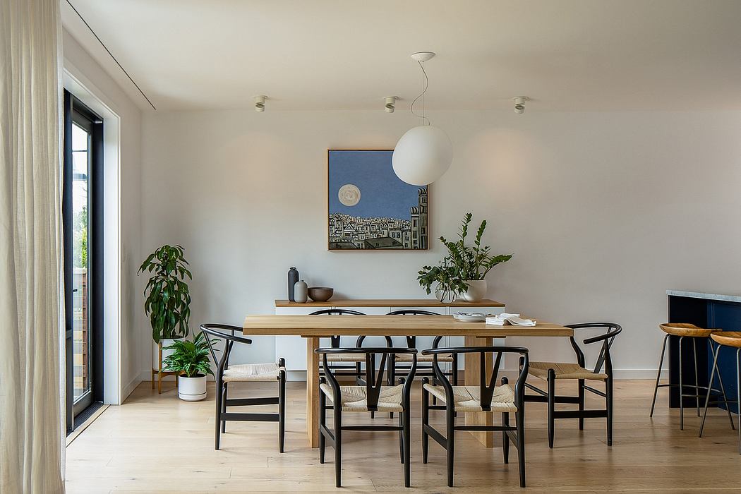 Minimalist dining room with wooden table, black chairs, and potted plants. Sleek pendant lighting.