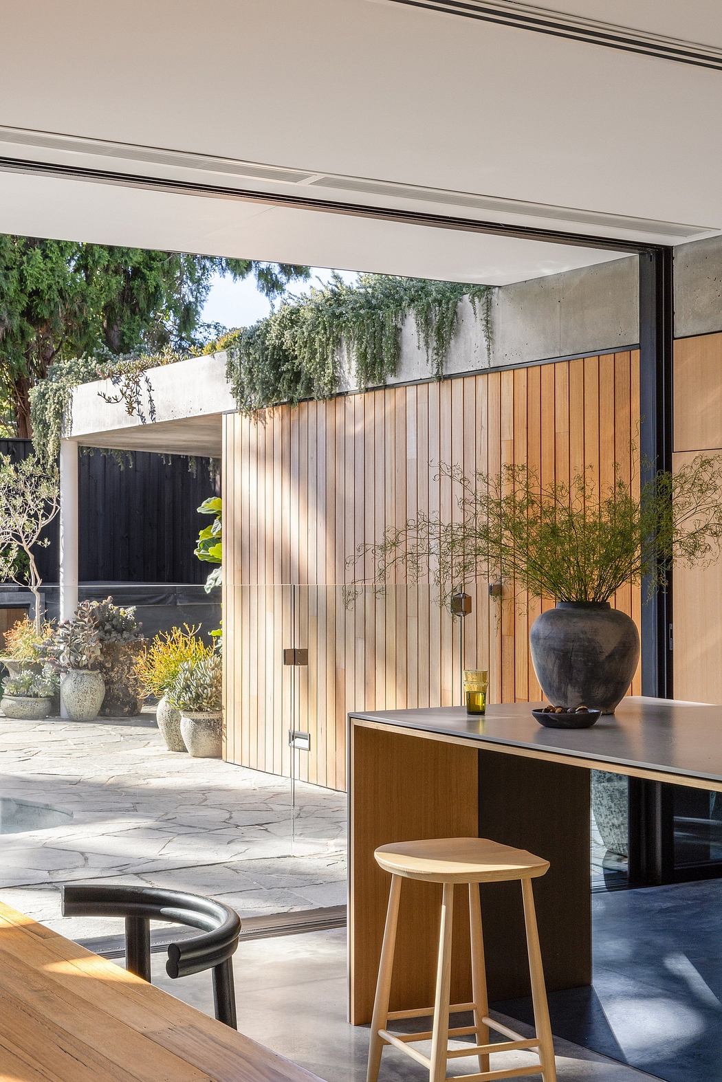 Sleek modern architecture with wooden panels, a kitchen island, and potted plants.