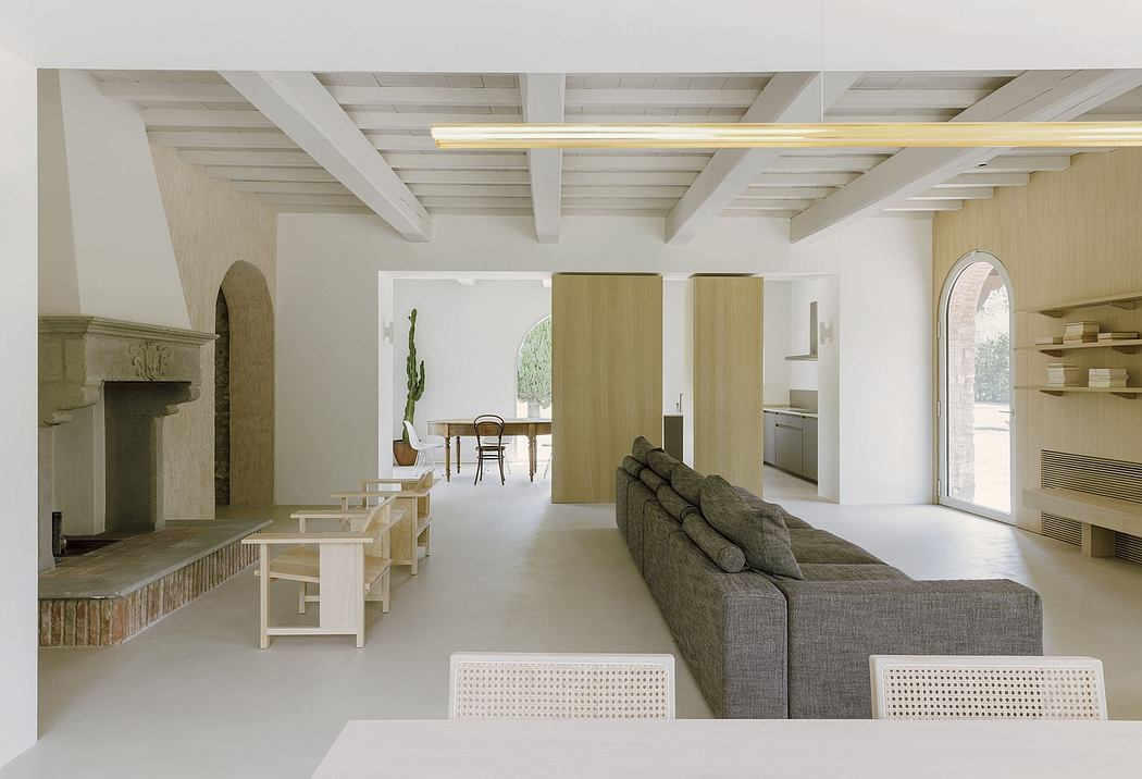 A bright, open-concept living space with exposed wooden beams, a cozy sectional sofa, and a dining area.