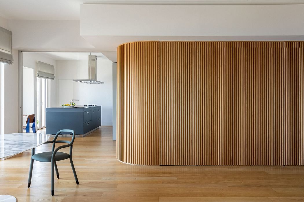 Minimalist modern interior with wooden paneled wall, kitchen island, and chair.