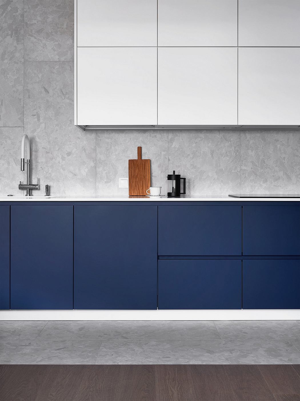 Sleek, minimalist kitchen design with navy blue cabinets, wooden cutting board, and modern fixtures.