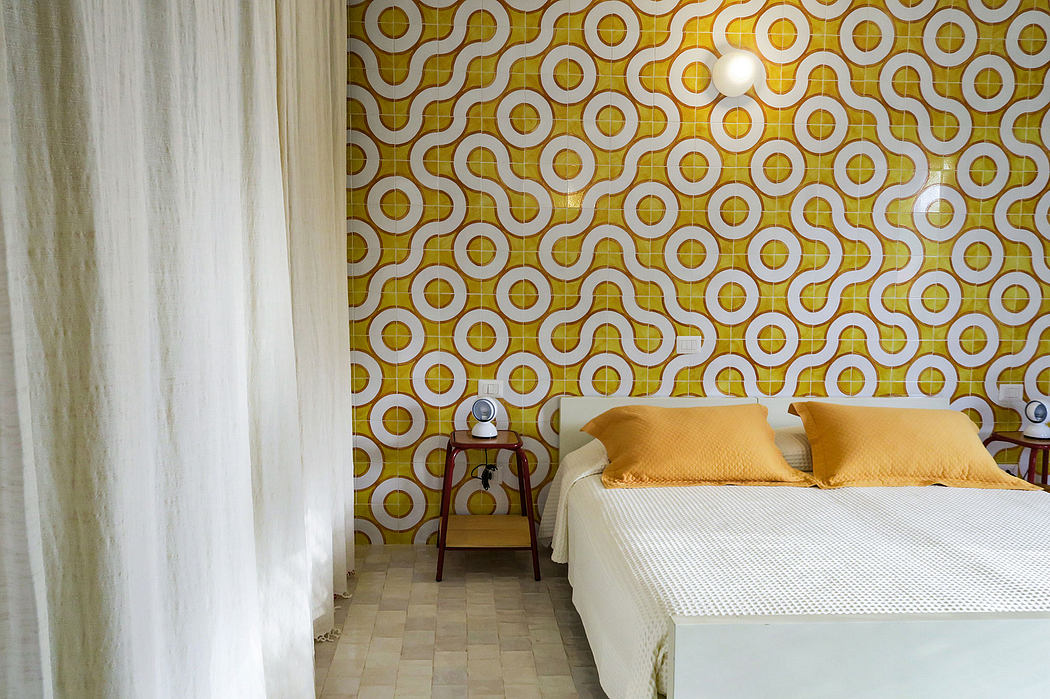 Vibrant geometric wallpaper, white bed, and wooden nightstand in this cozy bedroom.