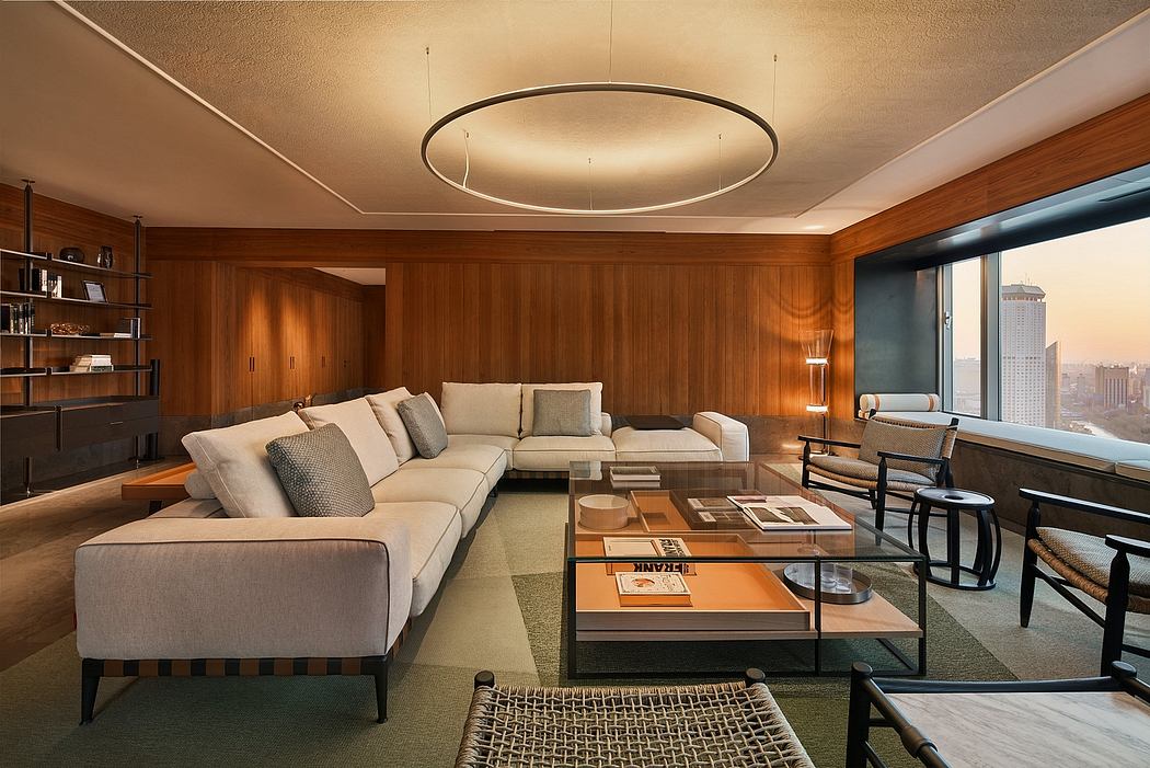 Warm-toned living room with a large sectional sofa, modern lighting fixture, and cityscape view.