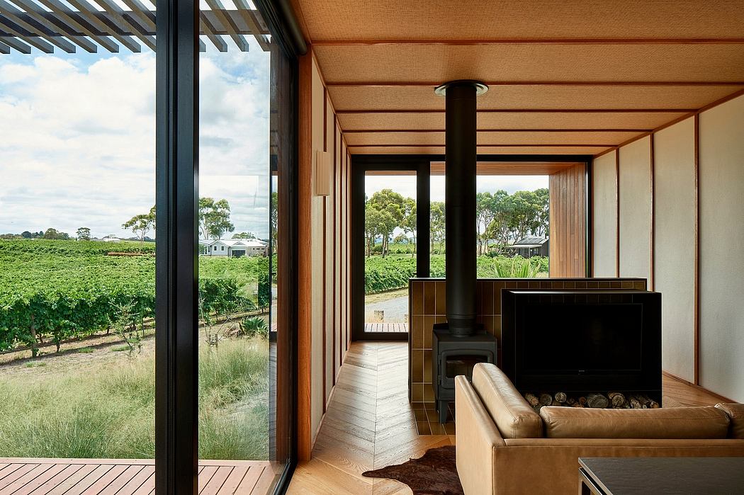 Modern wooden interior with panoramic vineyard view, fireplace, and deck.
