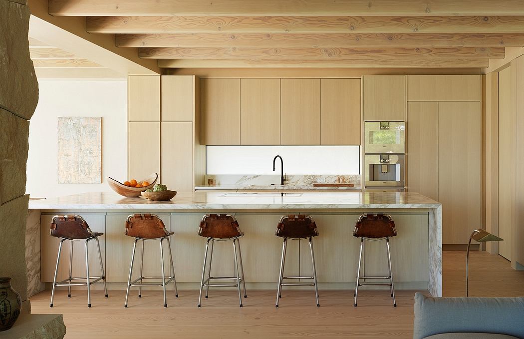 Spacious kitchen with wooden beams, marble countertop, and retro-inspired barstools.