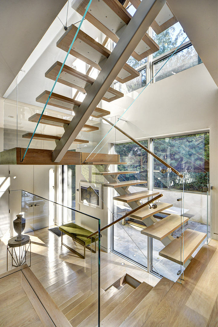Breathtaking open-plan interior with dramatic wooden staircase, glass walls, and natural lighting.