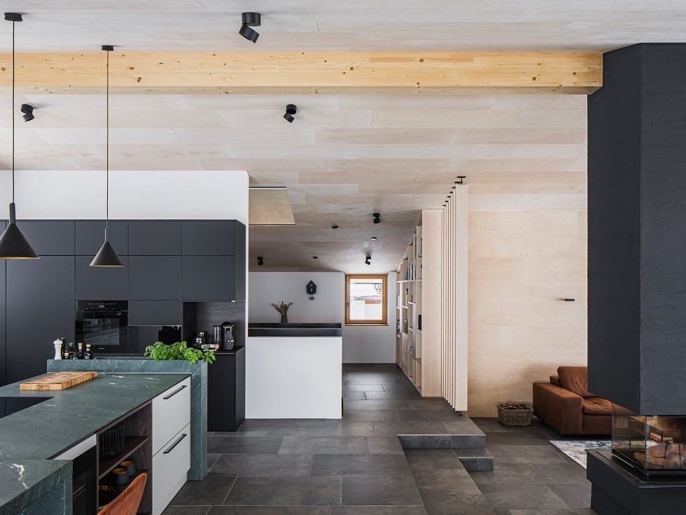 Sleek, modern kitchen with black cabinetry, marble countertops, and exposed wooden beams.