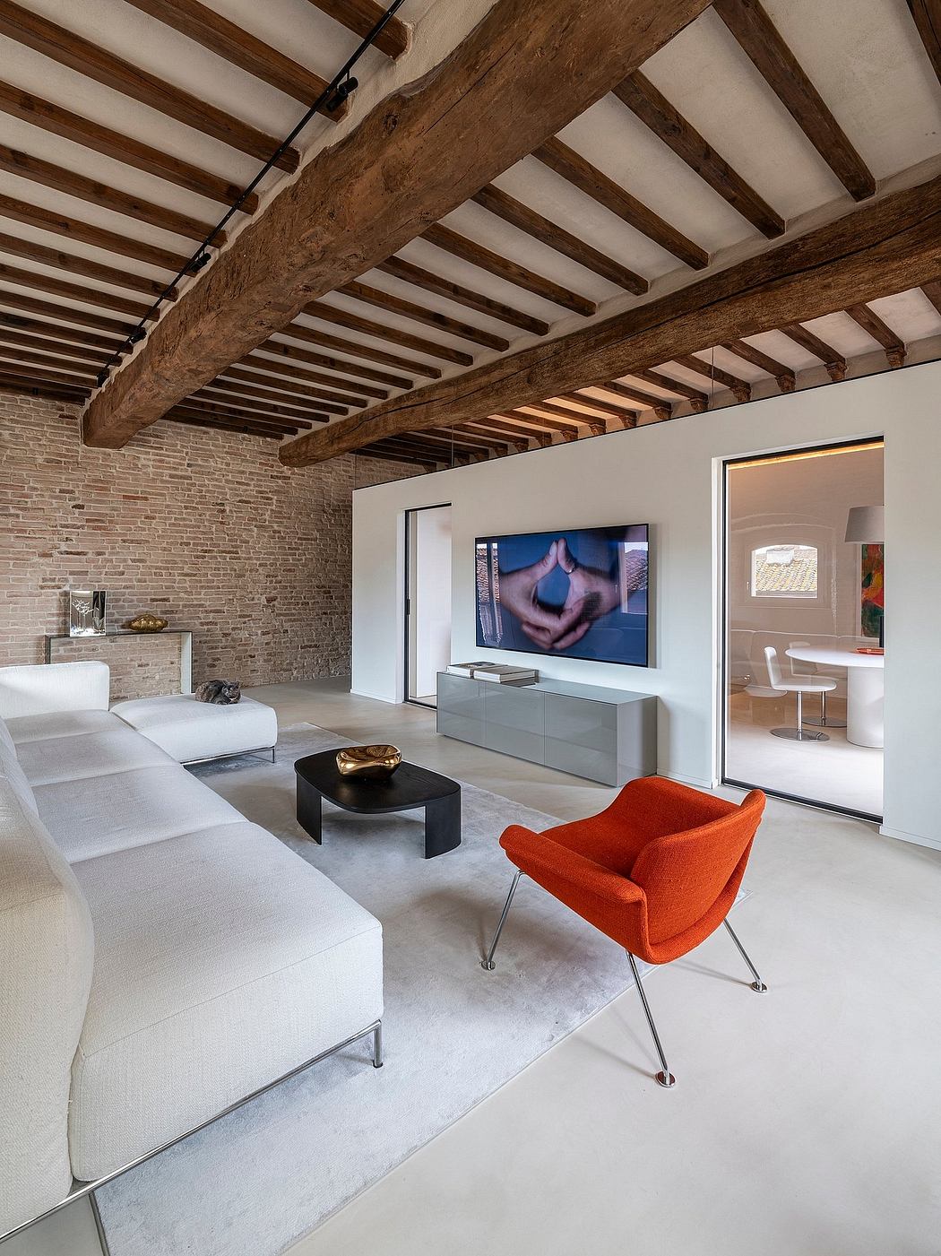 A modern living room with exposed wooden beams, sleek furnishings, and a large TV screen.