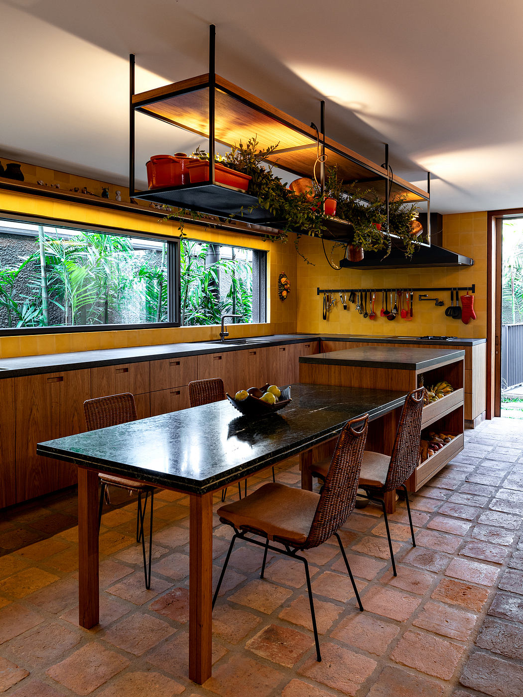 Warm, inviting kitchen with wood cabinetry, open shelving, and a stone tile floor.