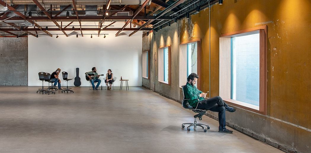 Large open-plan studio space with high ceilings, exposed beams, and concrete walls.