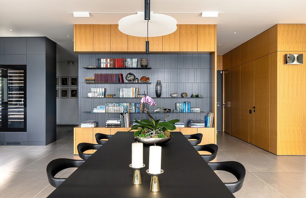 The image showcases a modern and stylish dining space with sleek wooden cabinets, shelves, and a large central light fixture.
