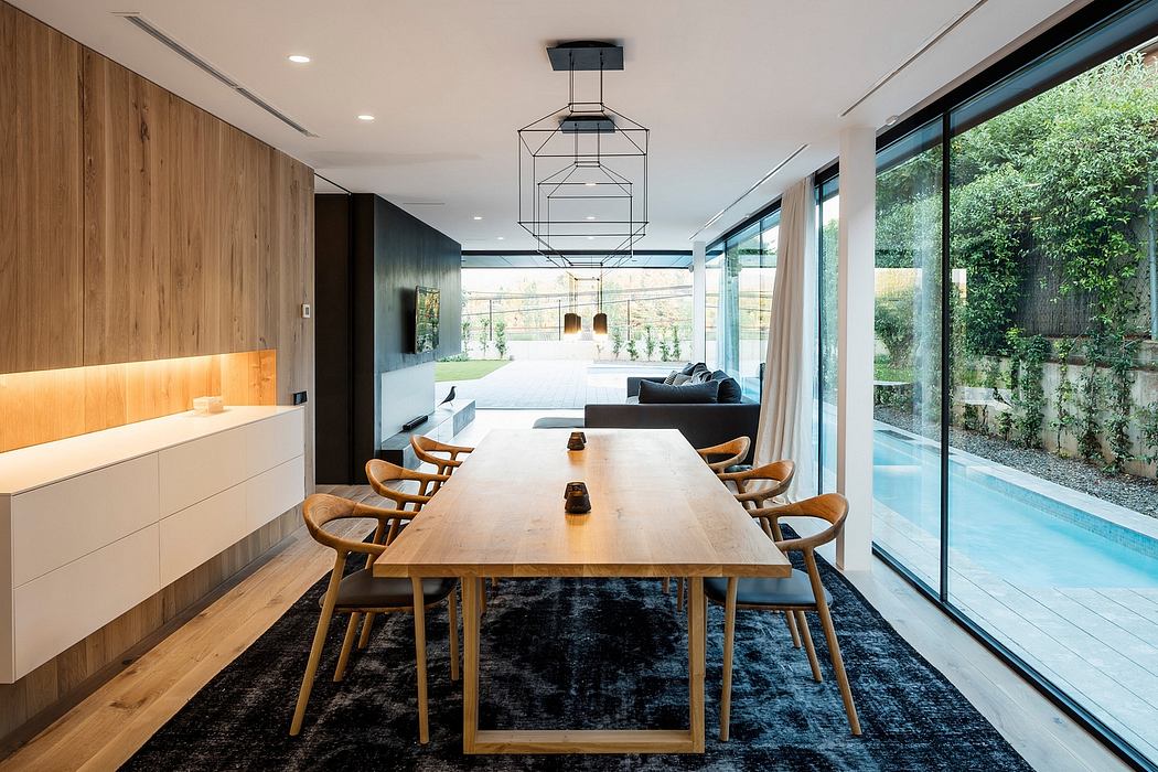 Minimalist dining room with wooden table, modern chairs, and floor-to-ceiling windows overlooking a pool.