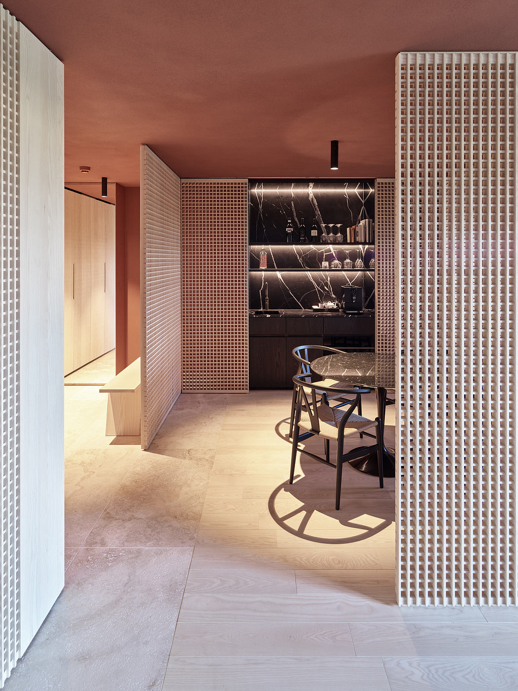 Sleek, modern kitchen with a black marble-clad wall, open shelving, and a minimalist chair.